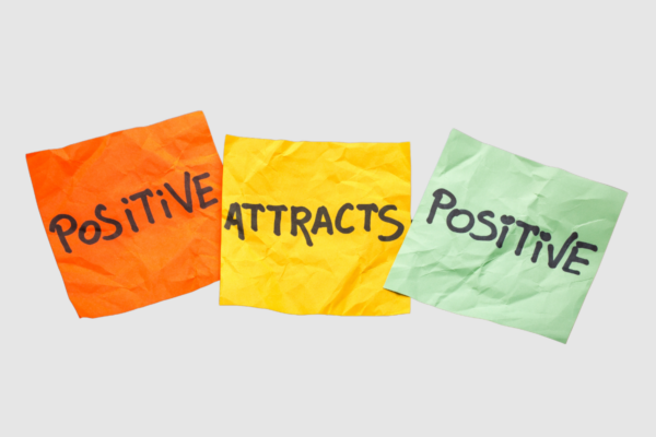 positive attracts positive steht jeweils einzeln auf einem Zettel mit unterschiedlichen Farben auf grauem hintergrund